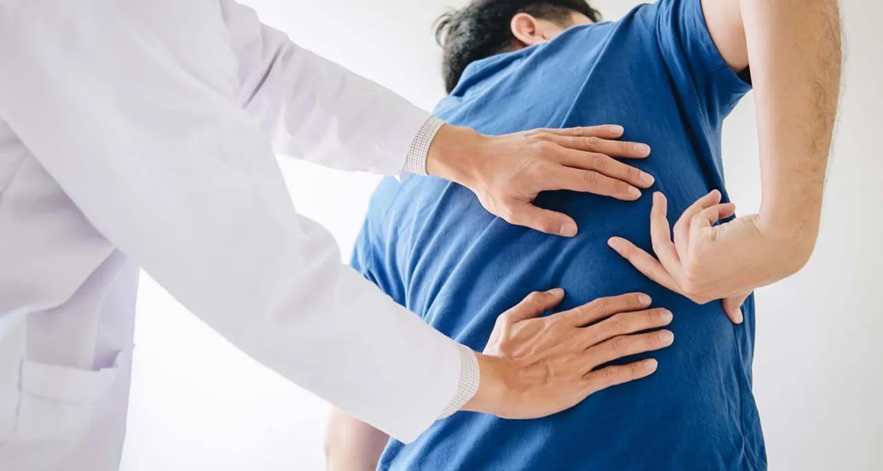 Clinician in a white coat with both hands placed on a patient's mid-back