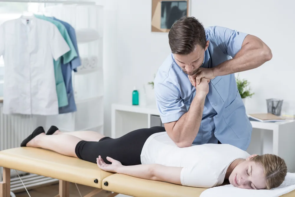 Chiropractor performing a neck adjustment on a woman lying on a table