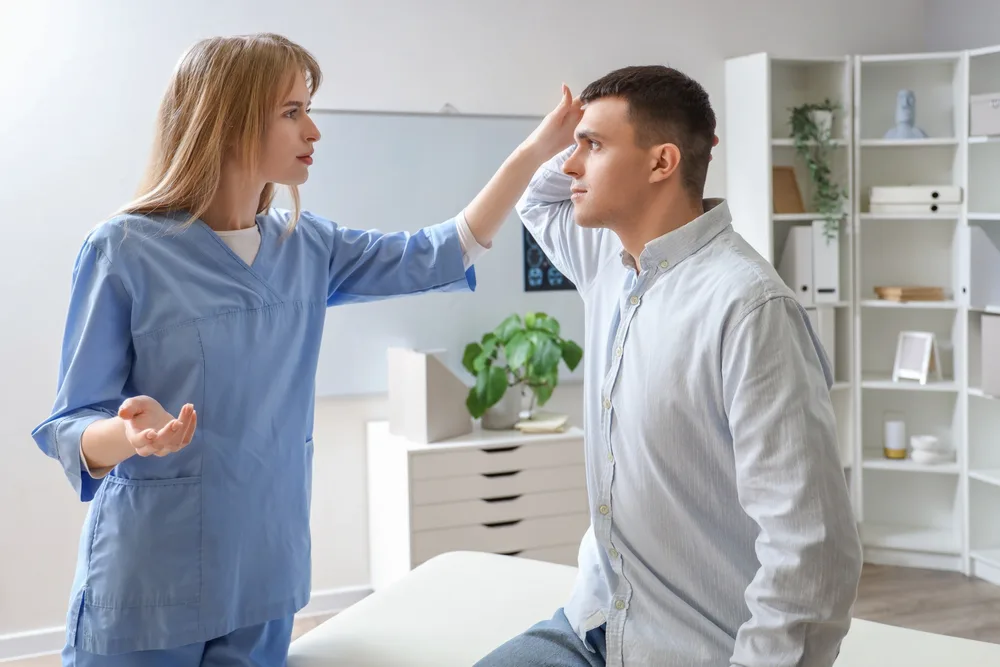 Clinician checking the neck movement of a standing man