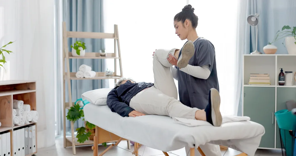 Therapist treating a patient lying on a table in a bright treatment room
