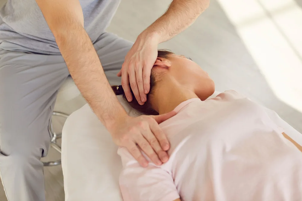 Therapist supporting the neck of a man lying on a treatment table