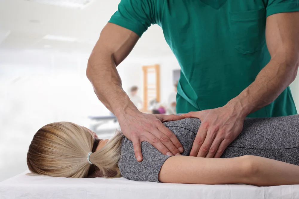 Therapist pressing on the lower back of a woman lying face down