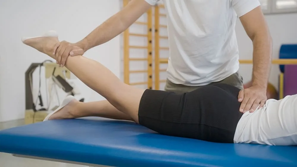 Therapist raising the straight leg of a patient on a treatment table