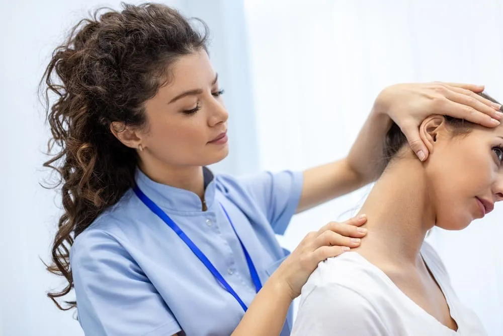 Clinician with both hands on the neck of a seated woman