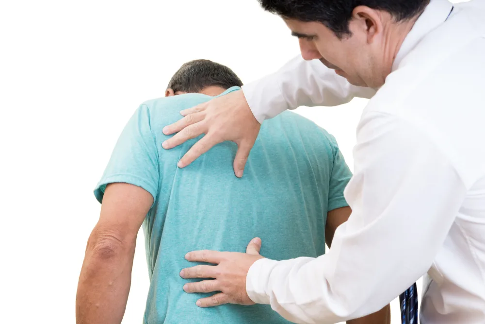 Clinician examining the upper back of a man in a blue shirt
