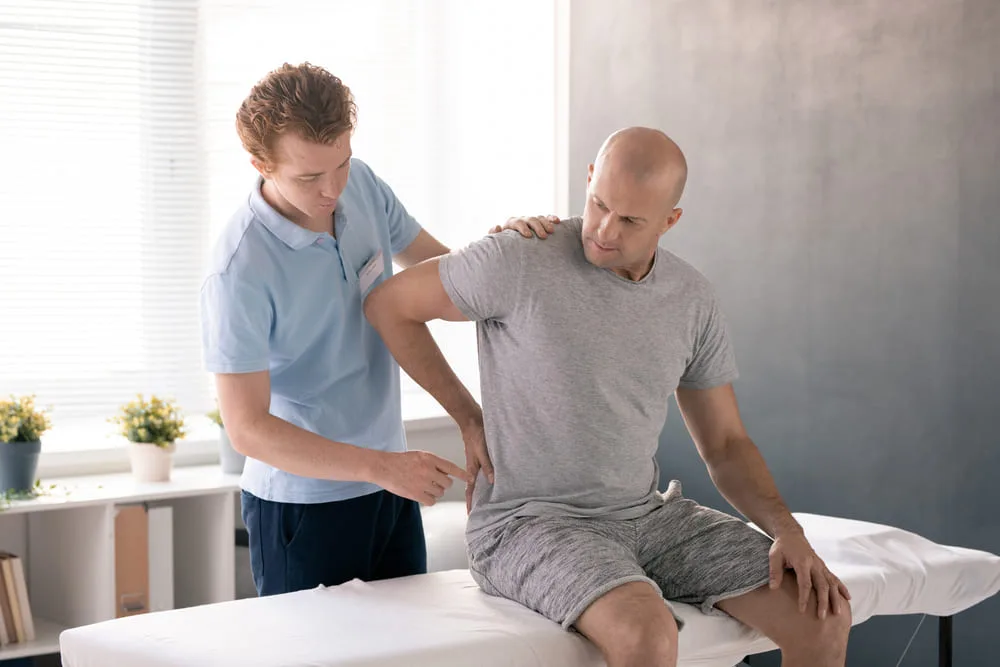 Therapist treating a man seated on a treatment table