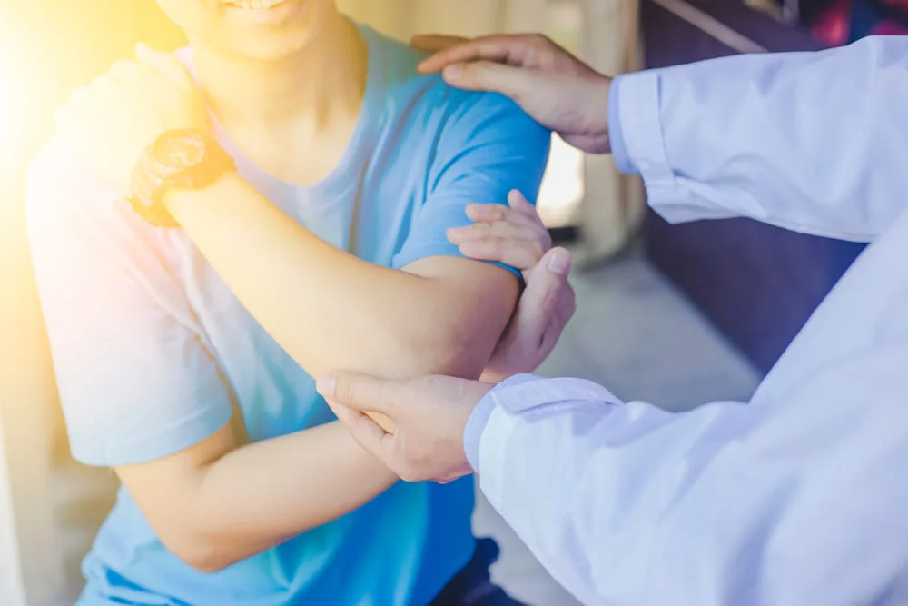 Close-up of clinicians' hands supporting a patient's shoulder