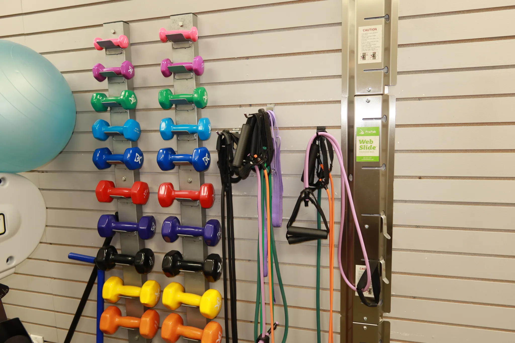 Racks of hand weights in graded sizes and resistance bands on the equipment wall