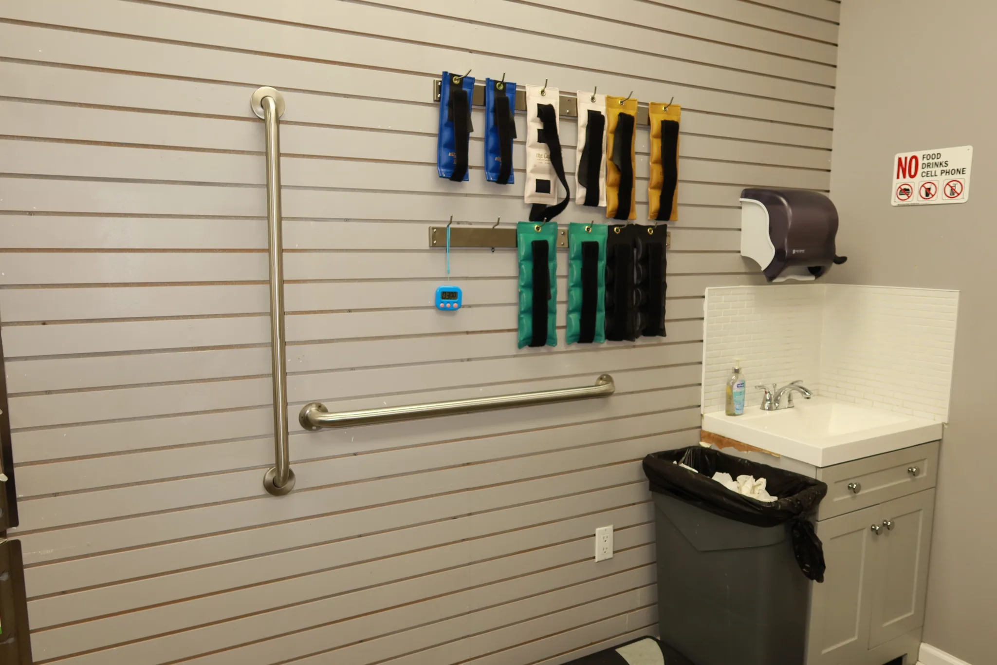 Equipment wall with ankle weights and supports, a handrail and a wash basin