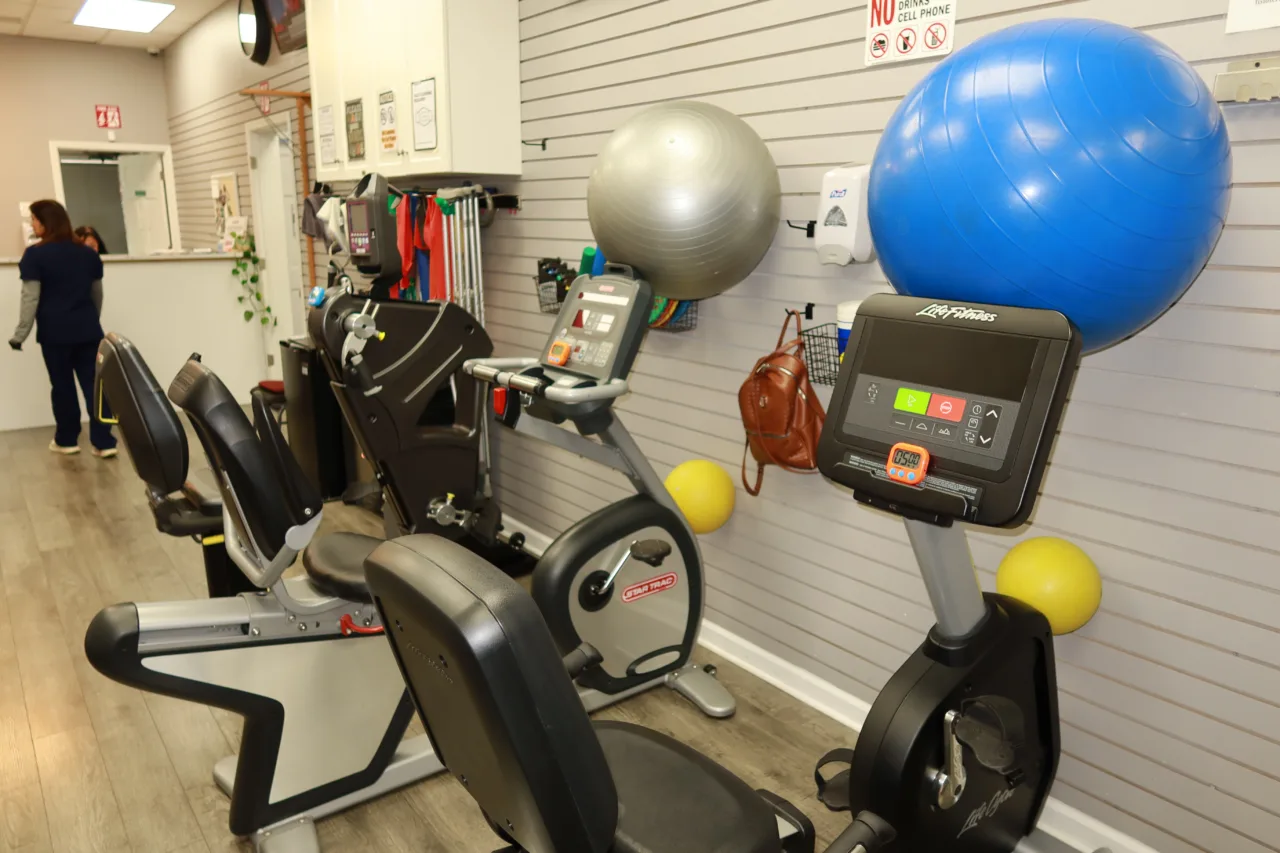 Exercise balls and cardio machines along the equipment wall, with the reception area beyond