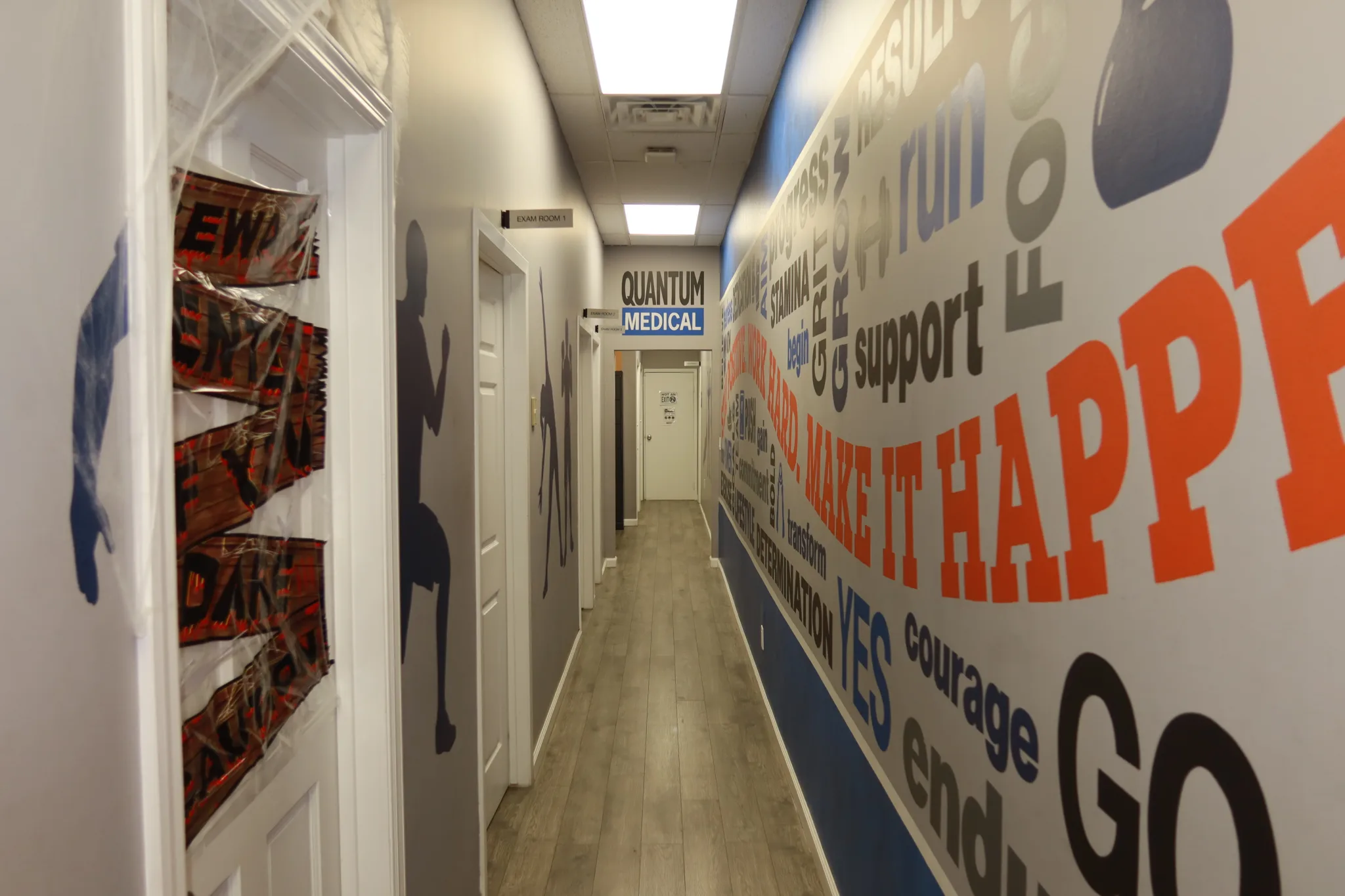 Corridor to the treatment rooms, lined with a motivational mural and the branded sign at the far end