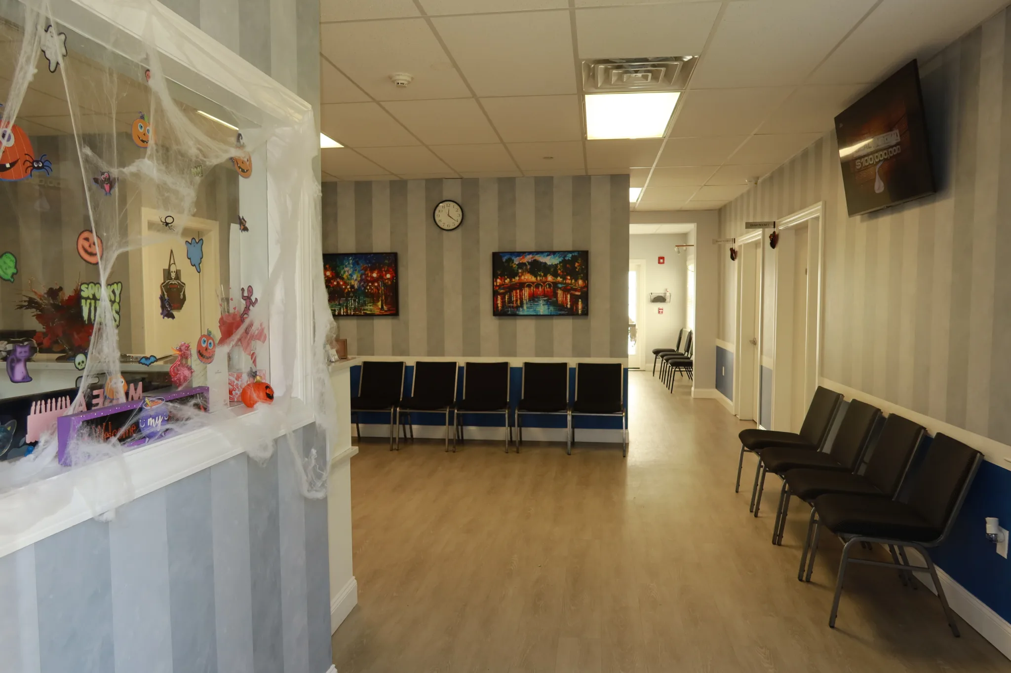 Waiting area with rows of chairs and framed artwork, and the reception window decorated for Halloween