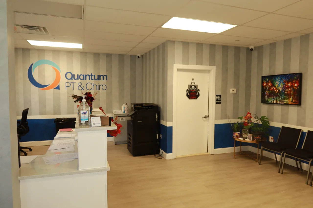 Reception desk under the Quantum PT & Chiro logo, with the waiting area alongside