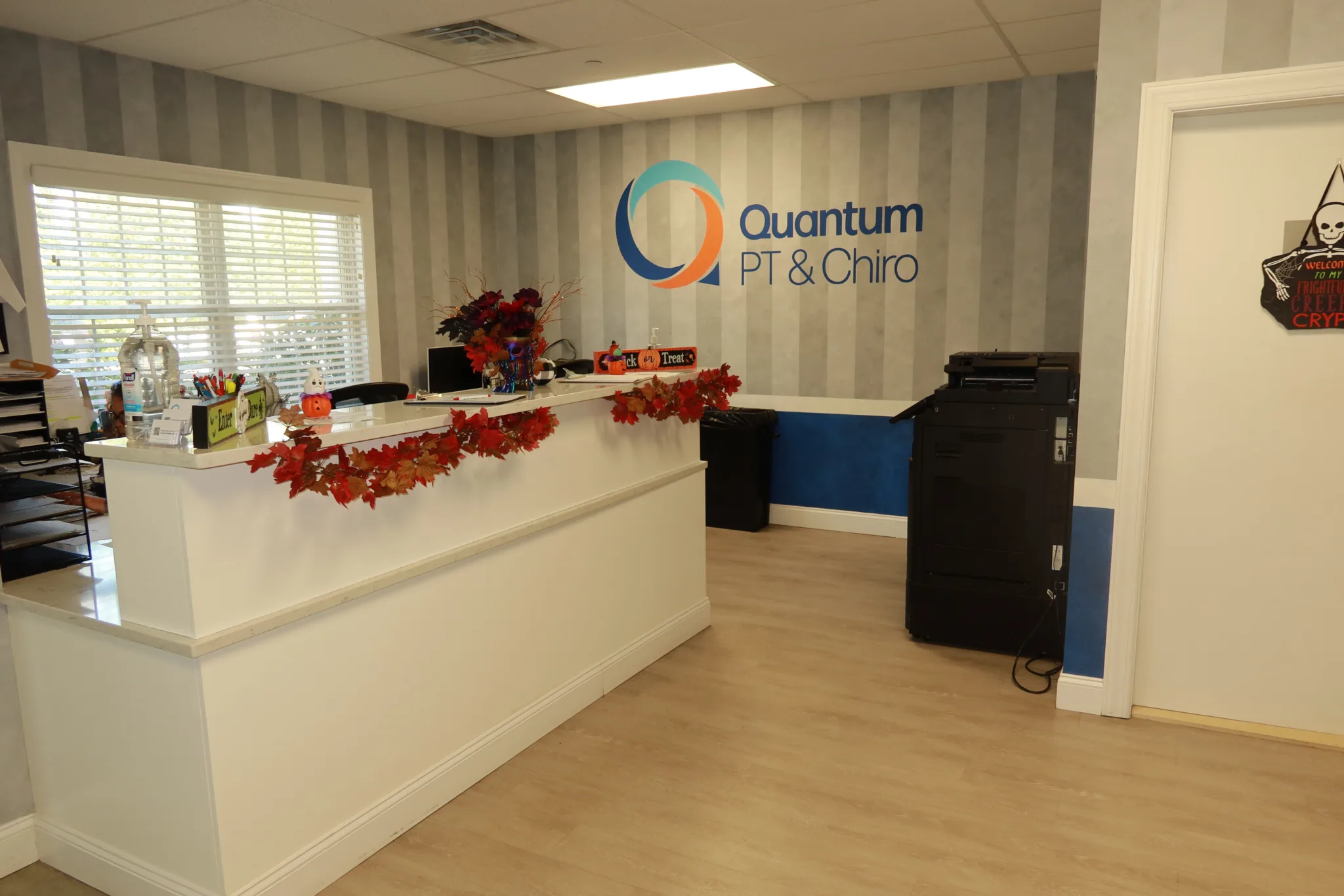 Reception desk under the Quantum PT & Chiro logo, decorated for autumn