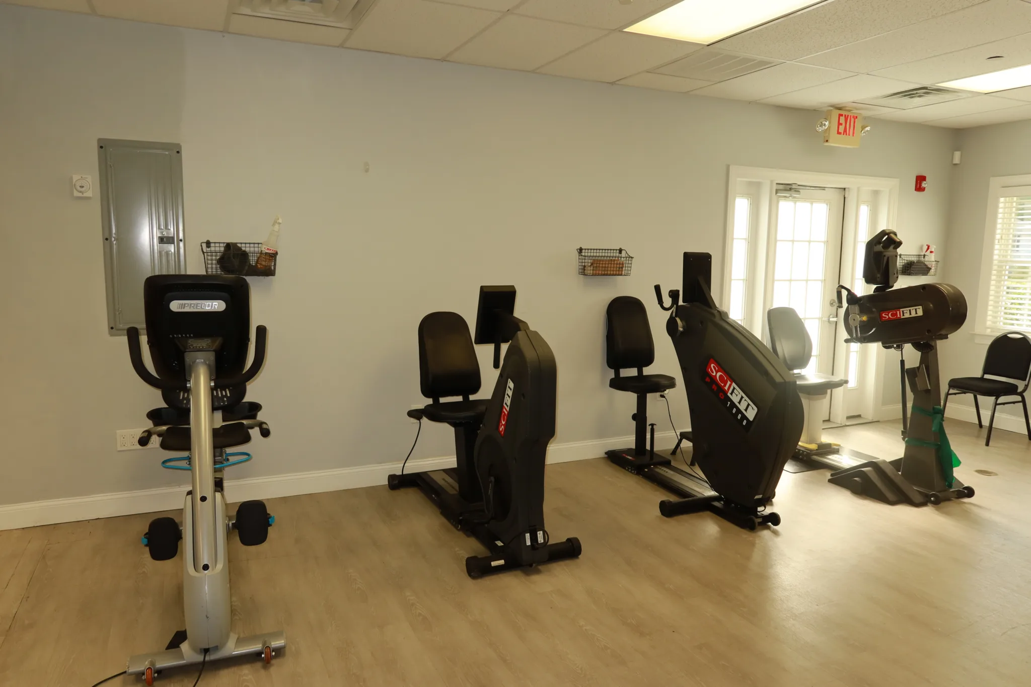 Recumbent bikes and upper body ergometers along the wall of the cardio room