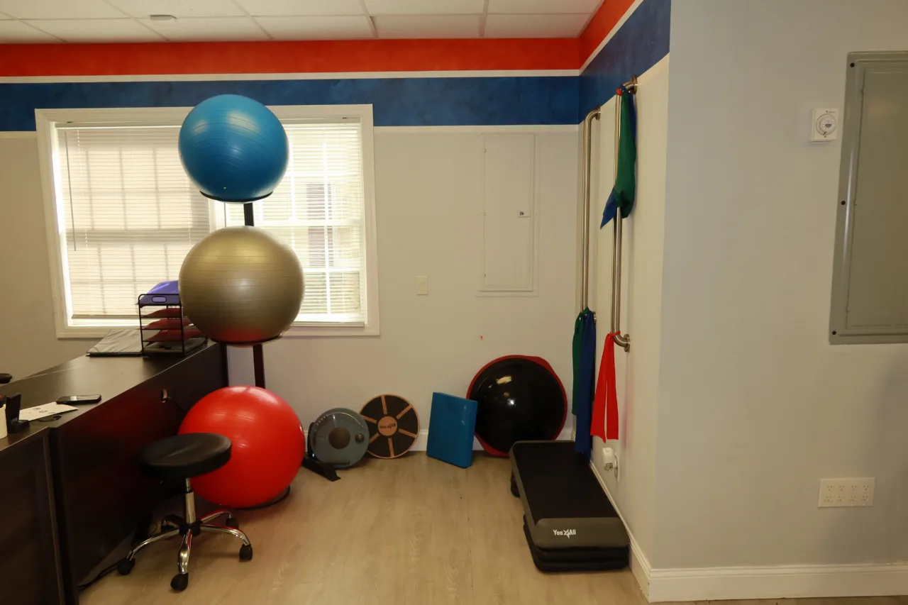 Corner with stacked exercise balls, weighted discs, a step platform and resistance bands on the wall