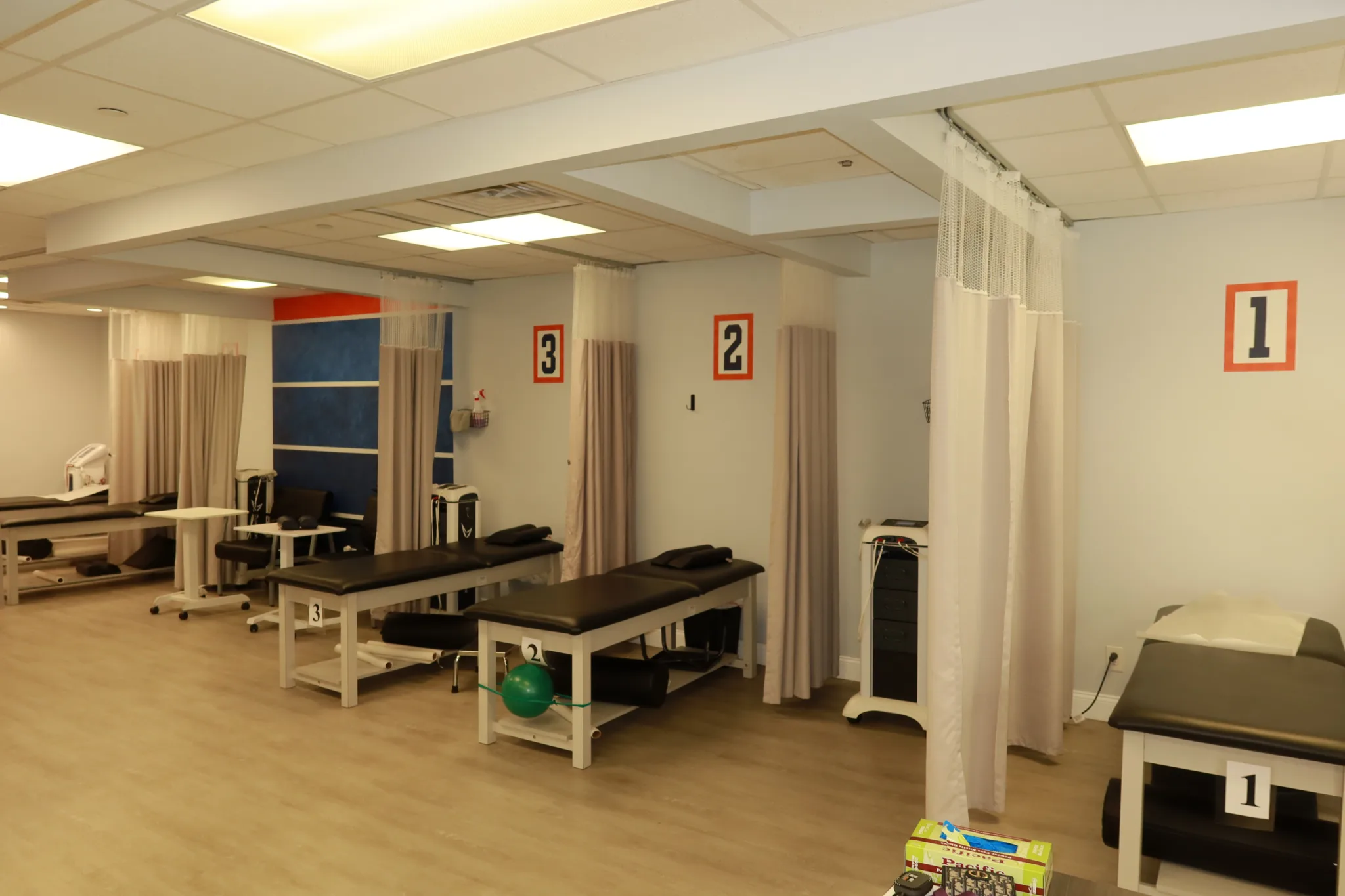 Treatment room with numbered bays and therapy tables behind privacy curtains