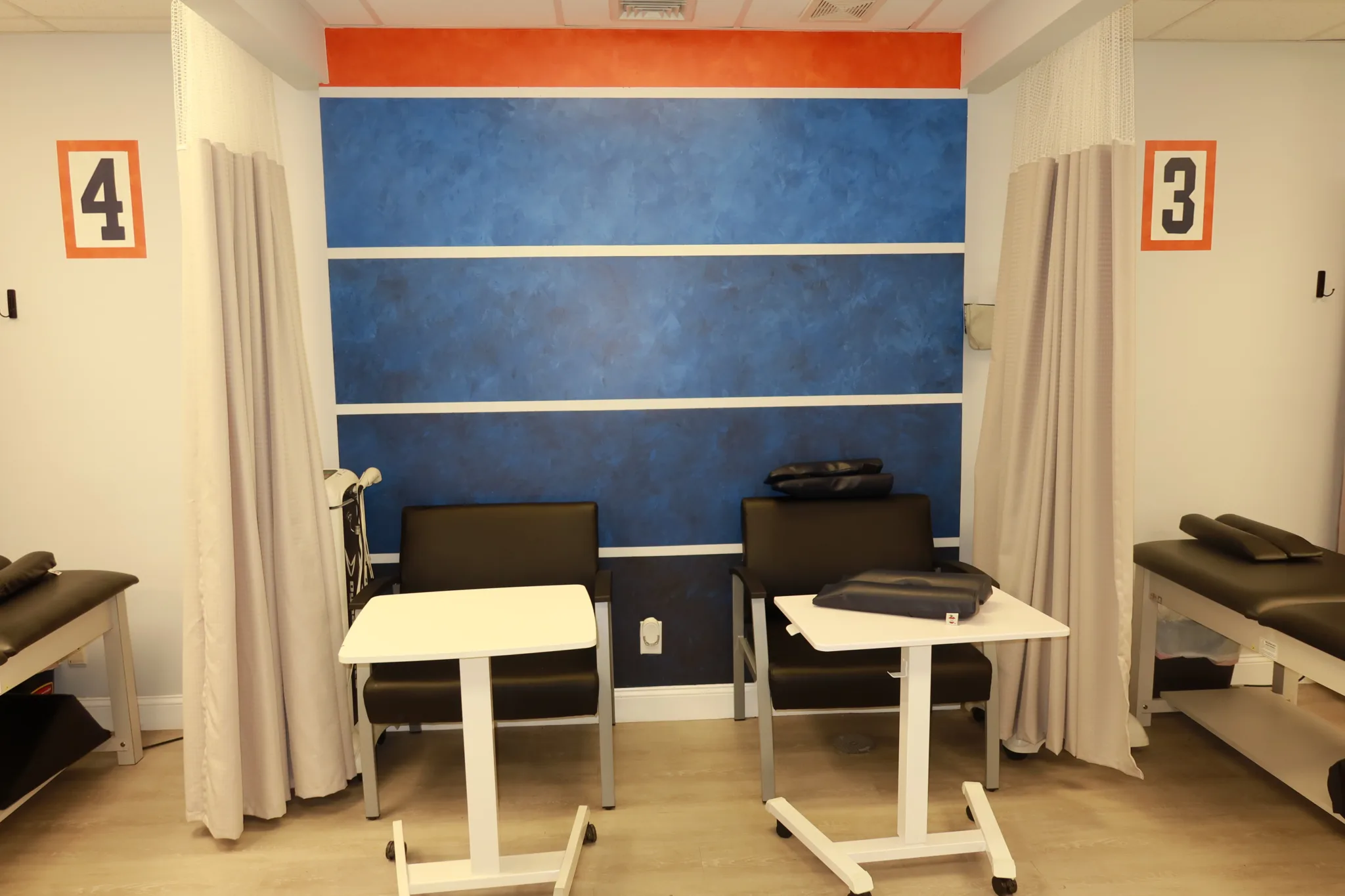 Numbered treatment bays four and three, each with a chair and an adjustable table