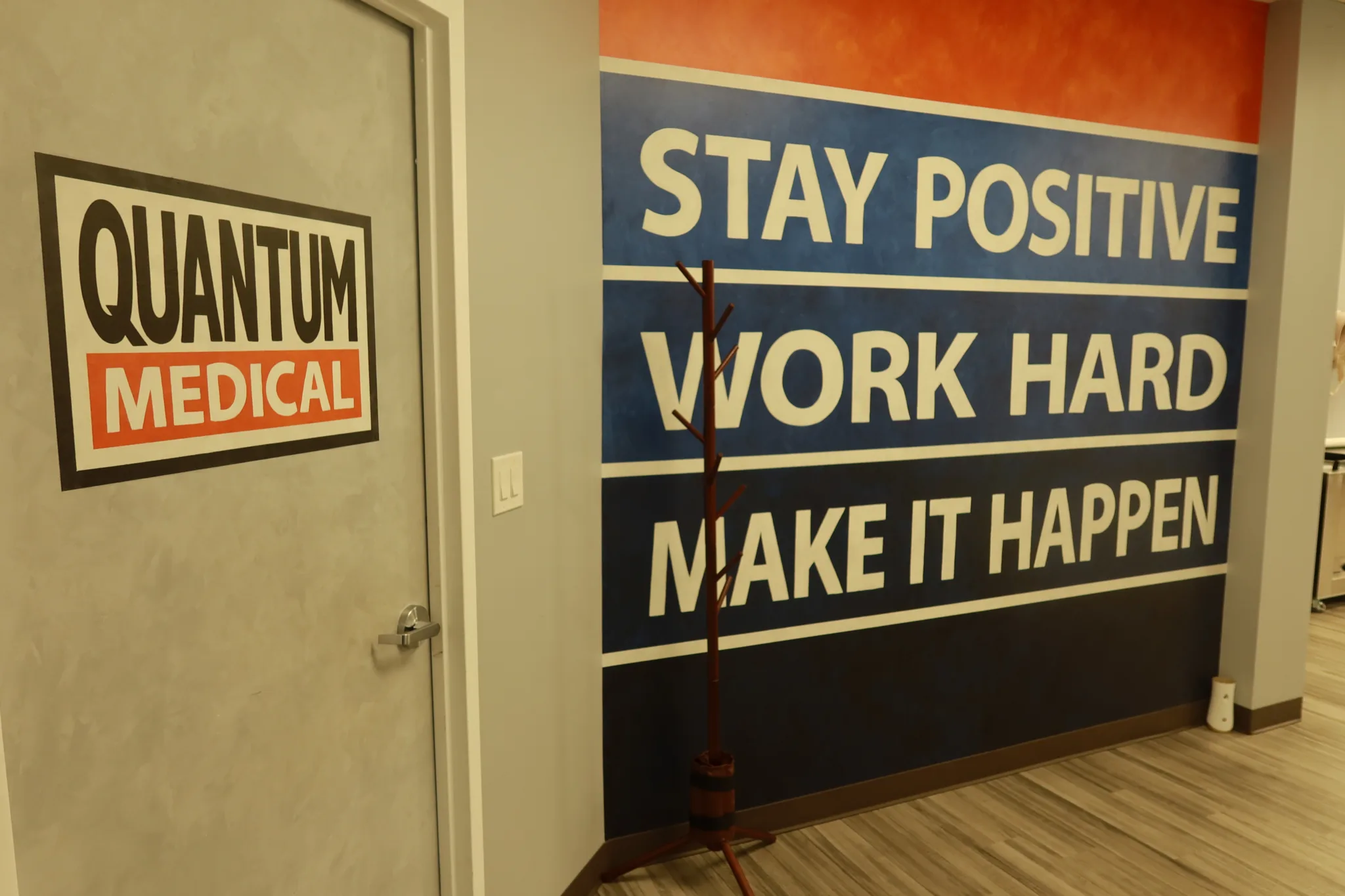 Branded wall sign beside a mural reading Stay Positive, Work Hard, Make It Happen