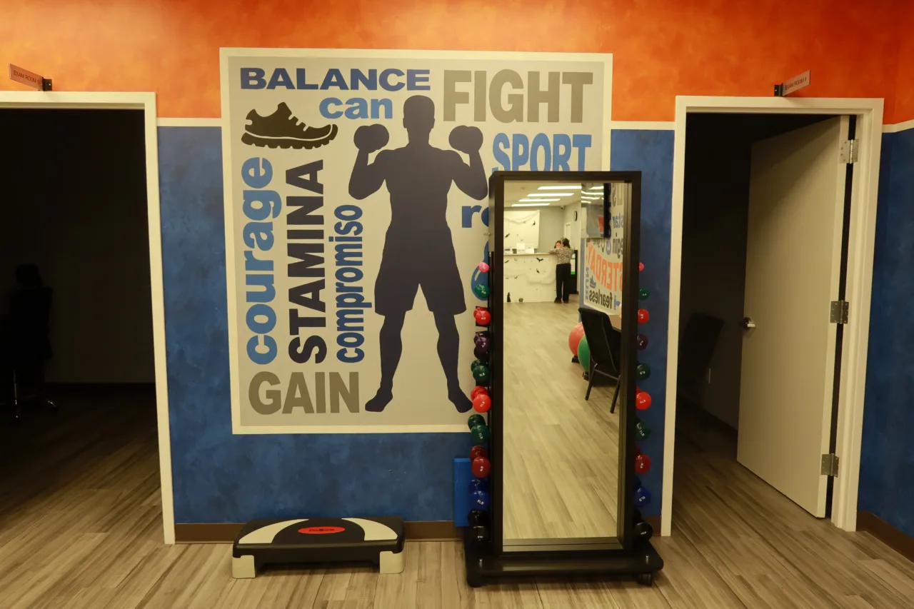 Bilingual motivational mural beside a full-length mirror, a dumbbell rack and a step platform