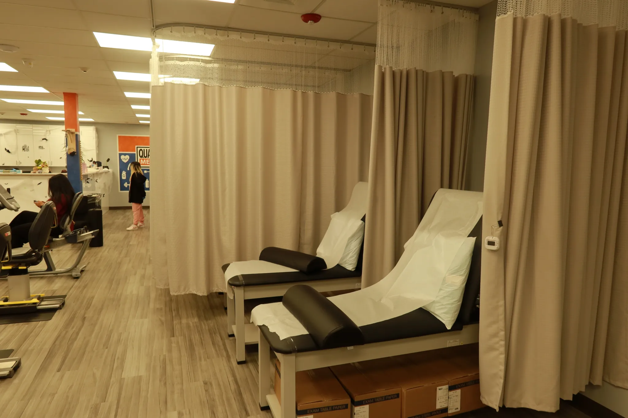 Curtained treatment bays with reclining therapy tables made up with fresh linen