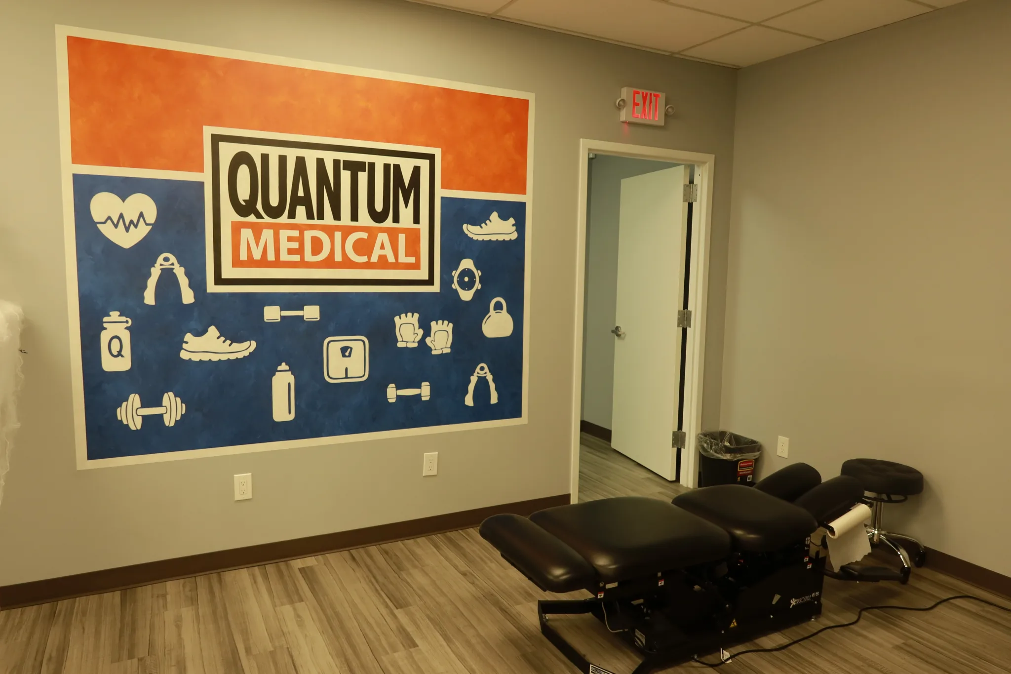 Chiropractic adjustment table in a private room beneath the branded wall mural