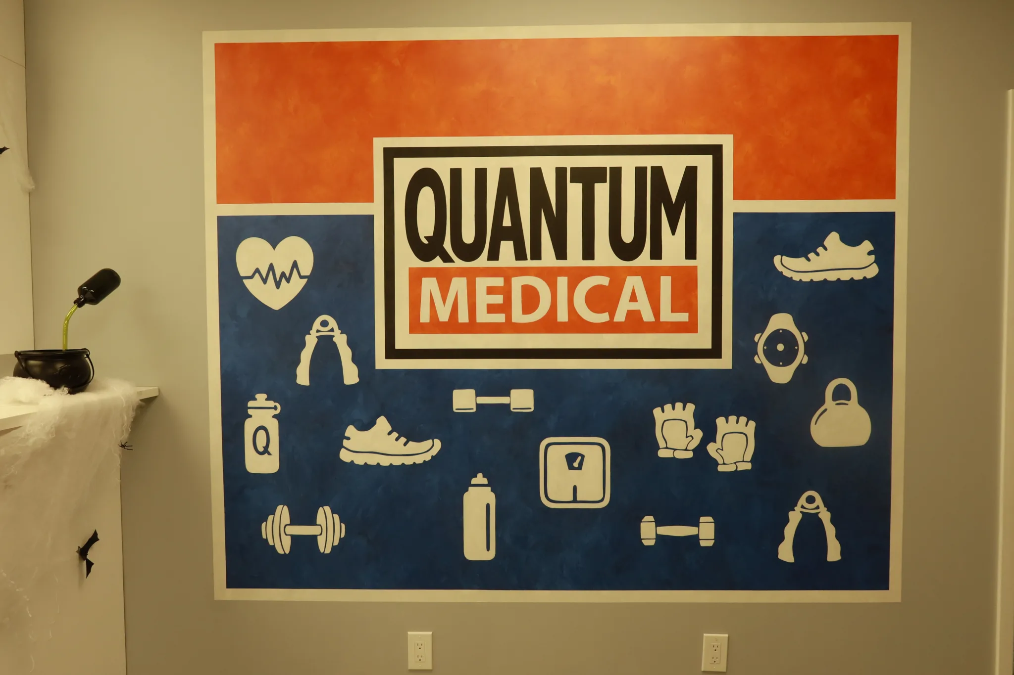 Branded wall mural with its band of health and fitness icons, beside a treatment table