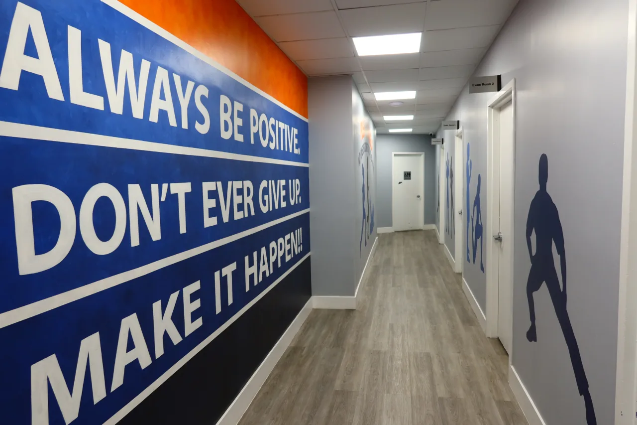 Corridor mural reading Always Be Positive, Don't Ever Give Up, Make It Happen, with athlete silhouettes beyond