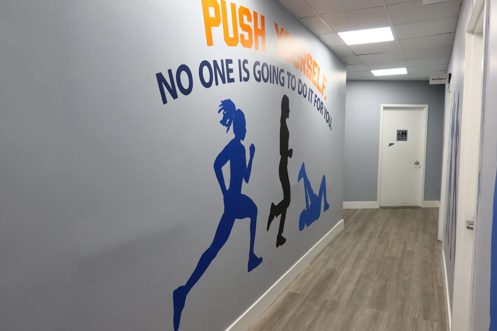 Corridor mural reading Push Yourself, No One Is Going To Do It For You, with painted runners