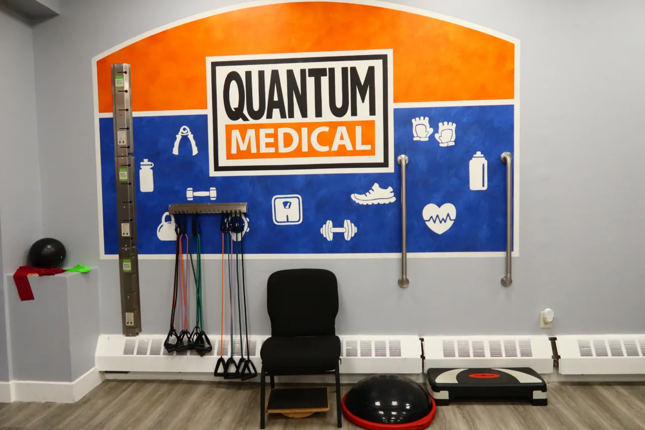 Exercise wall with a painted branded mural, resistance bands on a rack, a balance trainer and a step platform