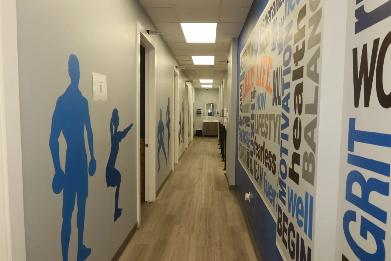 Corridor with blue athlete silhouettes facing a bilingual word mural
