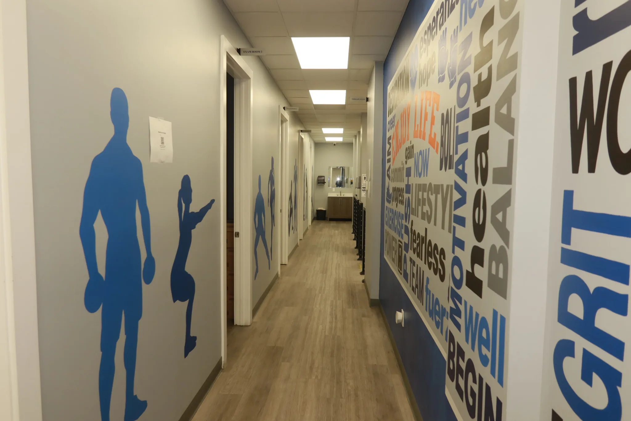 Corridor with blue athlete silhouettes facing a bilingual word mural