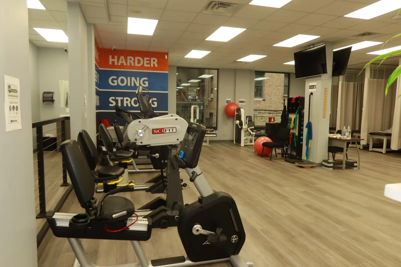 Cardio machines on the exercise floor, below the Working Harder, Keep It Going, Staying Strong mural