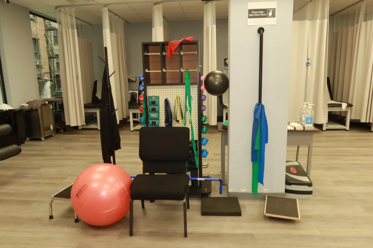 Exercise floor with a resistance band board, an exercise ball, step platforms and curtained treatment bays behind