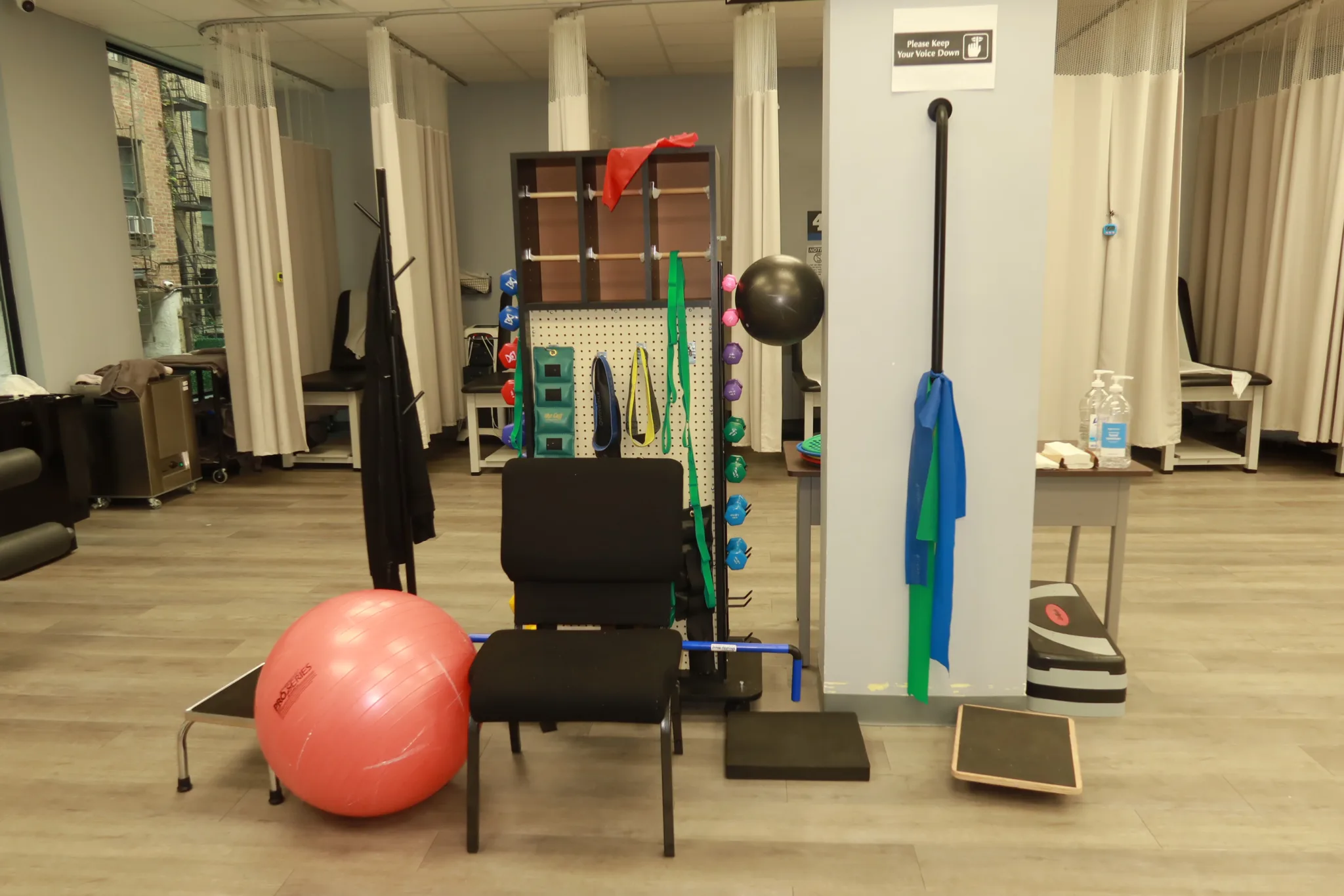 Exercise floor with a resistance band board, an exercise ball, step platforms and curtained treatment bays behind