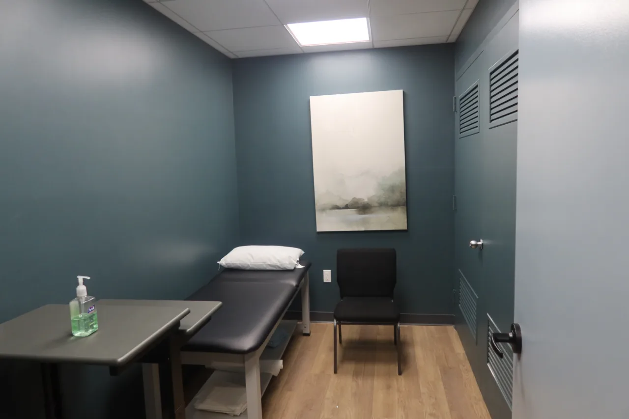 Private treatment room with a therapy table, a chair and a framed print