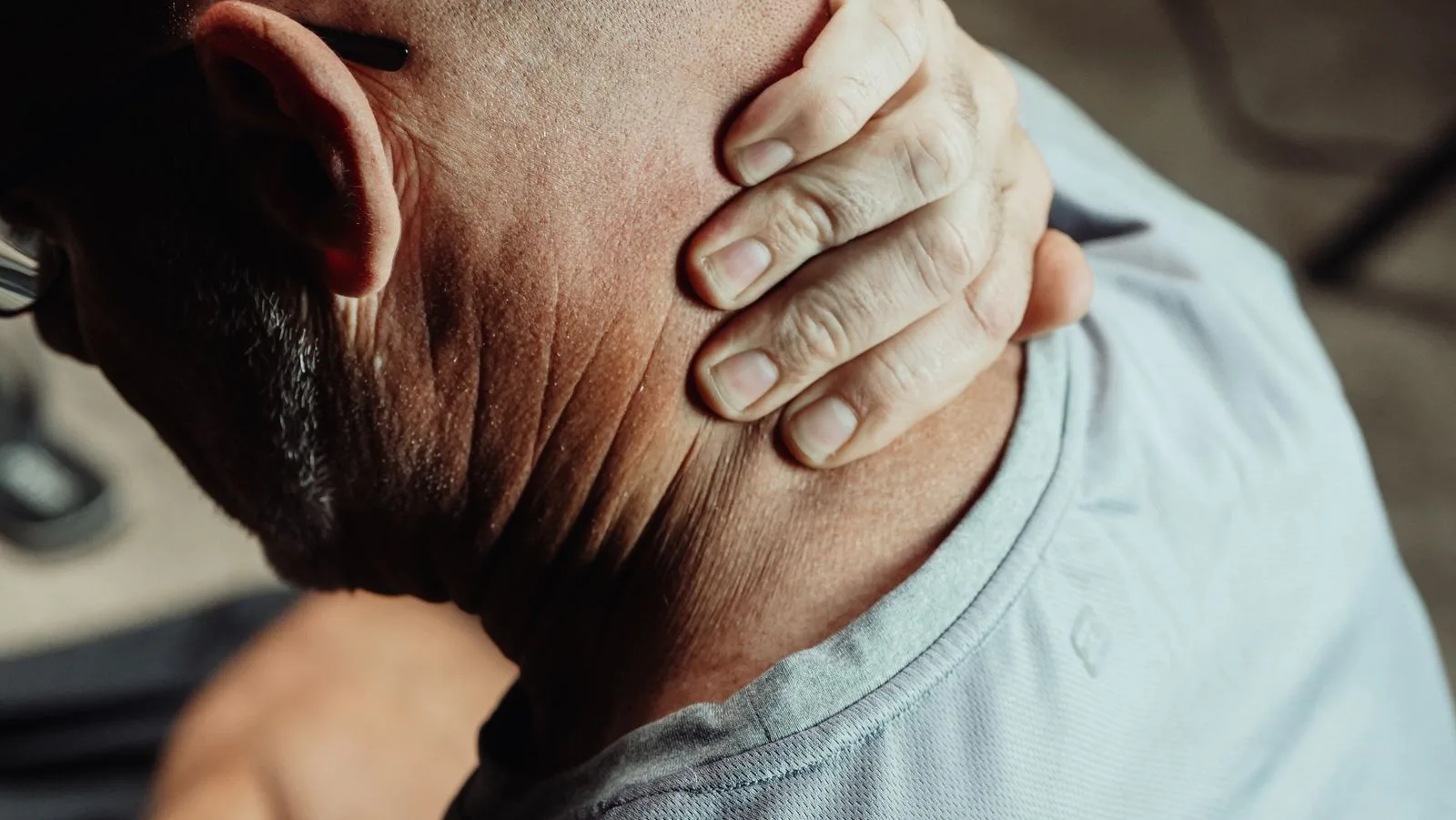 Close-up of a hand pressing the side of a stiff neck.