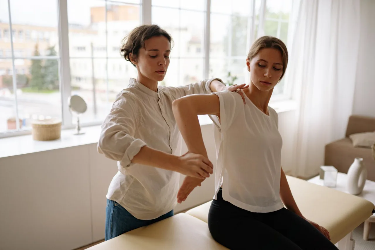 Therapist guiding a patient through a shoulder movement on a treatment table