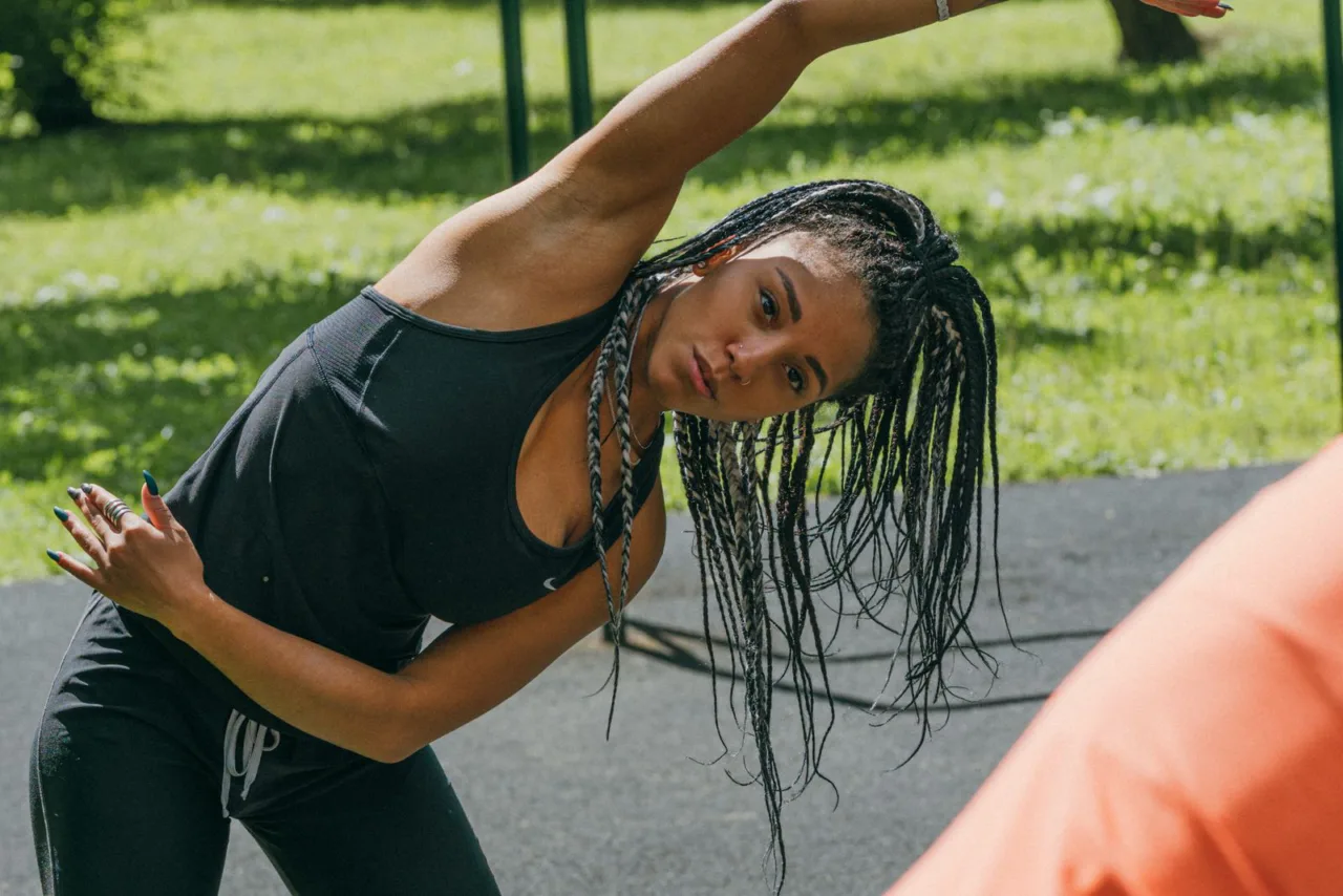 A woman stretches to one side during an outdoor warm-up.
