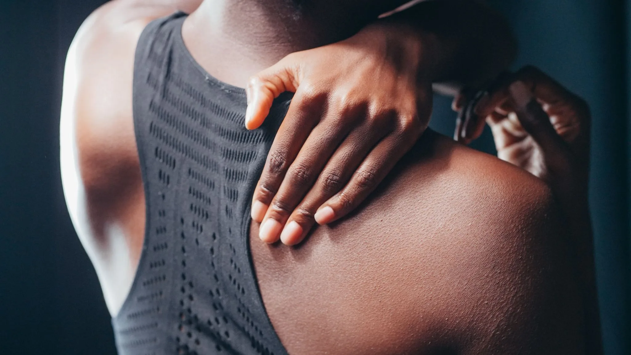 A hand presses on a sore shoulder blade.