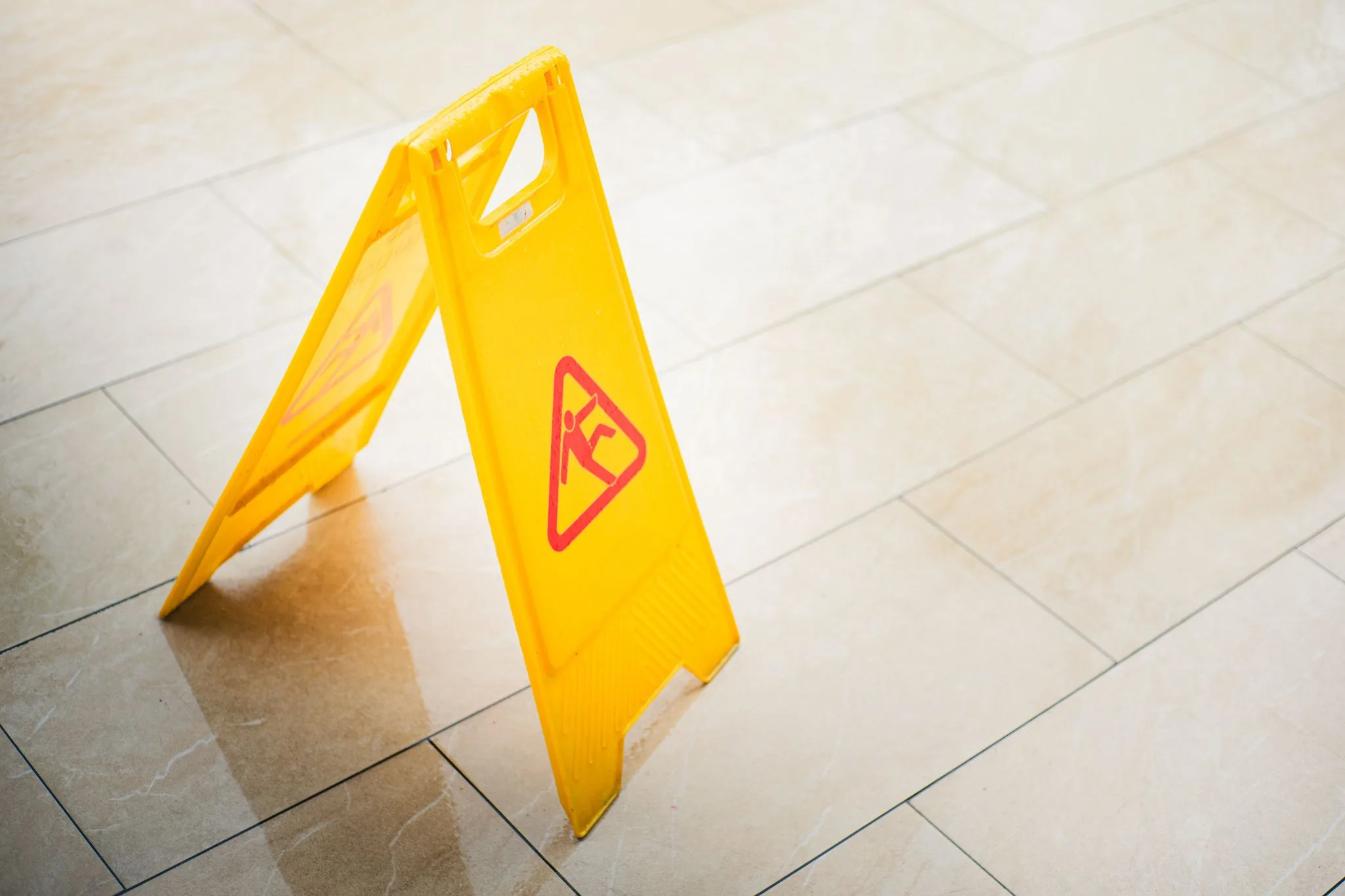 A yellow wet-floor caution sign on a tiled floor.